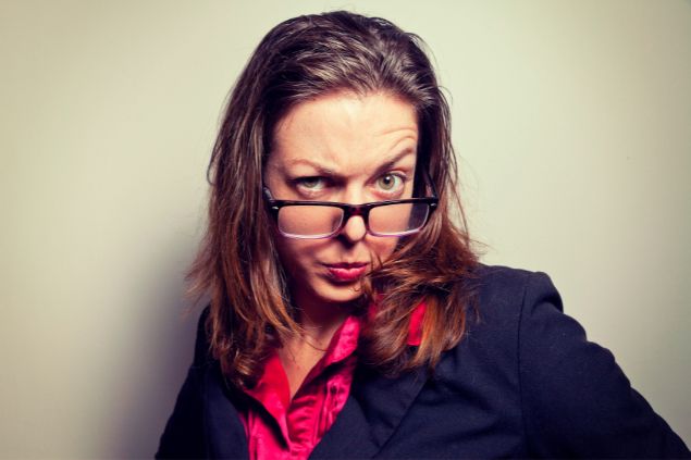 Imagem de uma mulher de óculos com feição de desconfiança