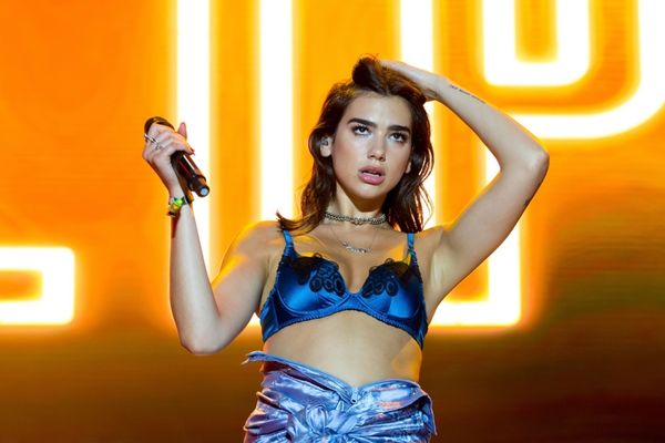Cantora Dua Lipa segurando microfone durante show