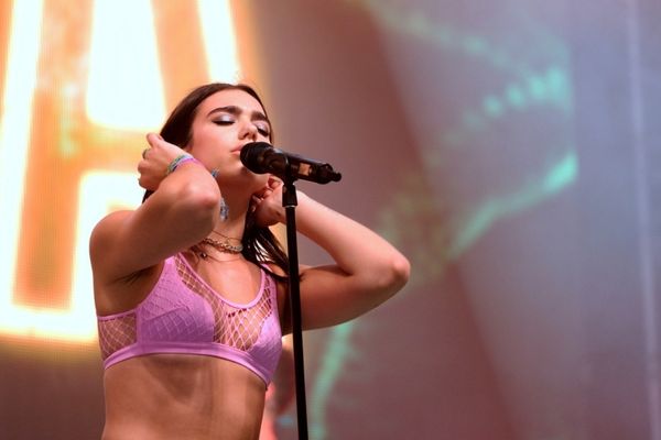 Dua Lipa de olhos fechados cantando durante um show
