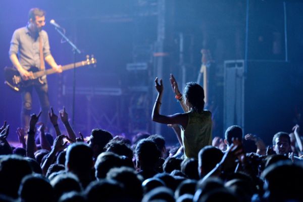 Fã em evidência sentada no ombro de um amigo em um show 