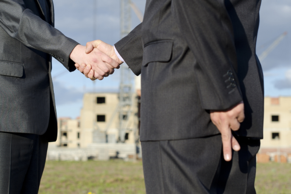 Homens brancos apertando as mãos e a outra mão cruzando os dedos.