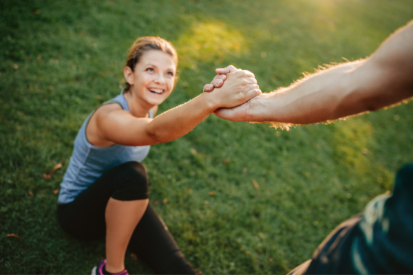 Homem dando a mão para ajudar uma mulher a se levantar