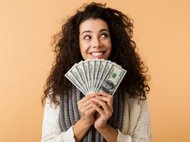 Menina segurando leque de dinheiro nas mãos