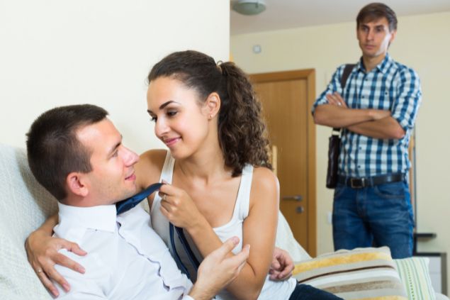 Imagem de uma mulher traindo seu marido com um homem com roupas sociais em casa