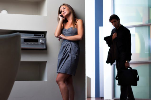 Imagem de uma mulher falando no celular e sorrindo e um homem querendo ouvir sua conversa com semblante triste