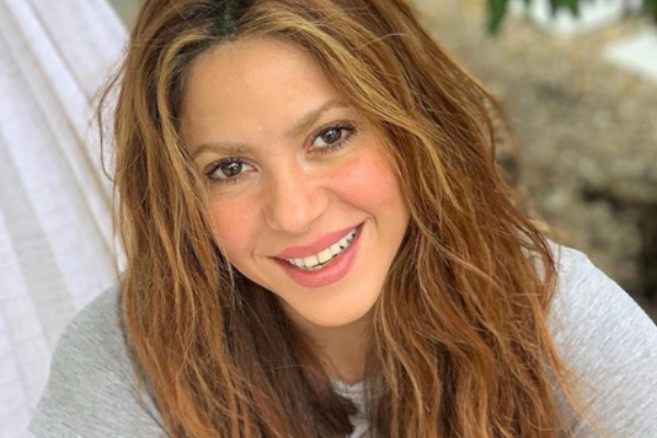 Shakira sentada olhando para frente sorrindo 