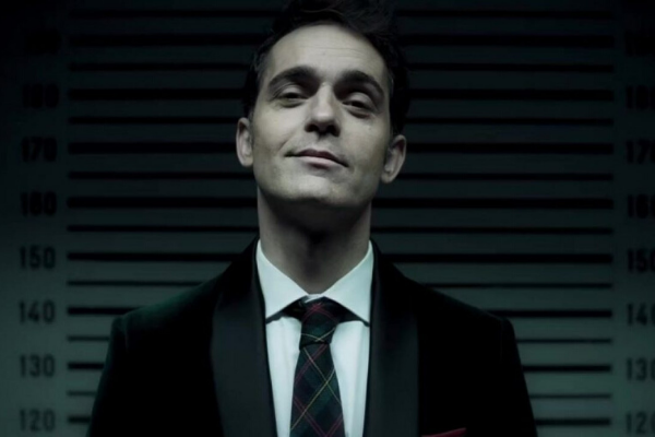 Berlin sorrindo olhando para frente usando terno e gravata