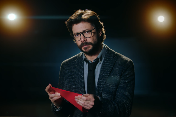 O Professor olhando para frente usando terno e segurando papel