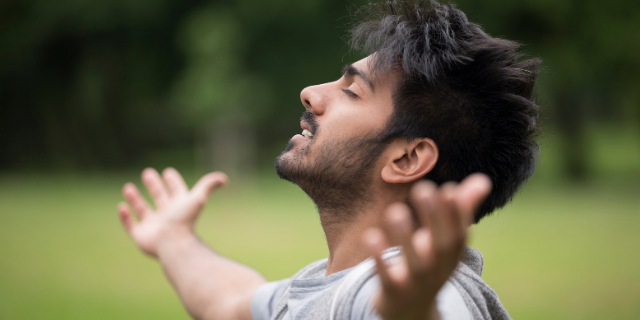 Homem orando com as mãos abertas