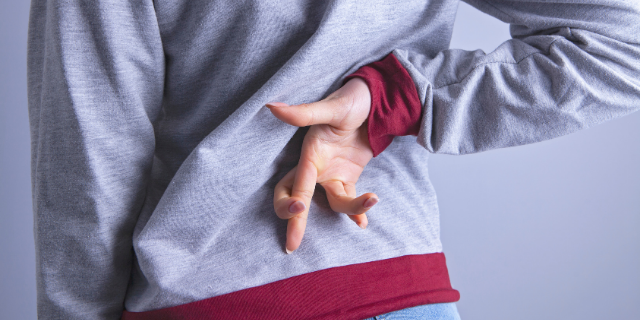 Pessoa cruzando os dedos nas costas, em sinal de mentira