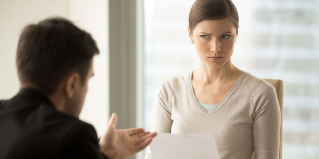 Mulher olhando desconfiada para homem durante entrevista