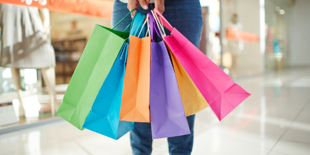 Pessoa carregando diversas sacolas coloridas em um shopping