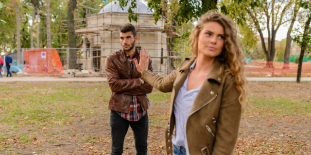 Mulher com expressão irritada para um homem. Os dois estão em um parque