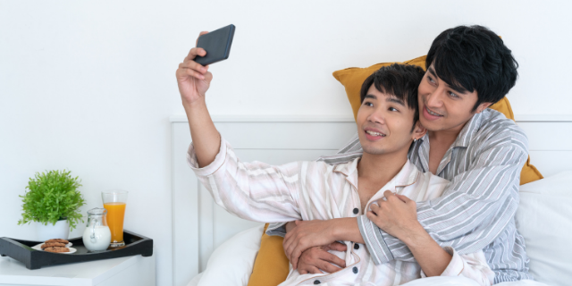 Casal na cama tirando uma selfie juntos
