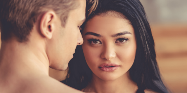Homem e mulher, um na frente do outro. A mulher olha fixamente para a câmera