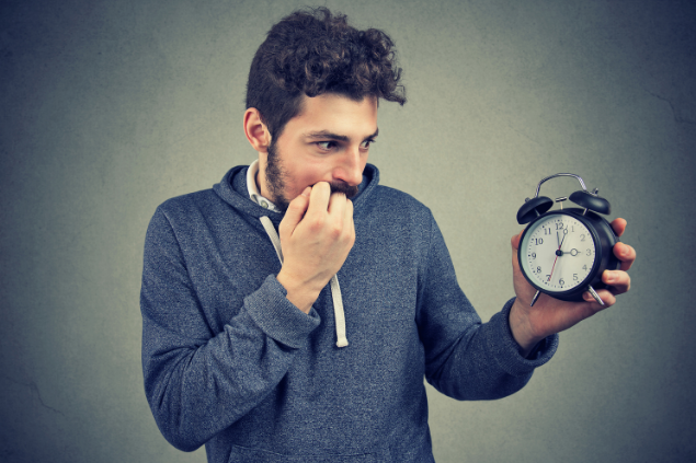 Homem segurando relógio com expressão ansiosa