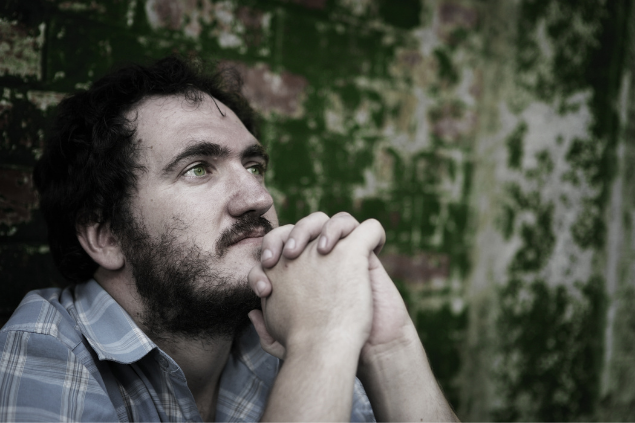 Homem apoiando a cabeça com as mãos e semblante reflexivo.