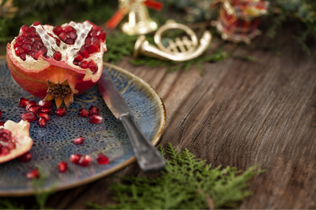 Romã cortada em cima de um prato, em uma mesa decorada