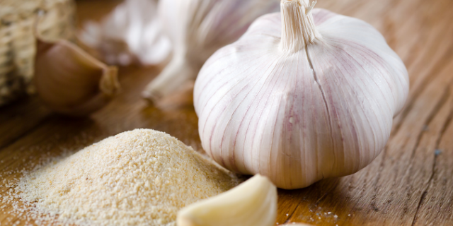 Anna1311 / Getty Images / Canva Cabeça de alho e um punhado de sal em cima de uma mesa de madeira