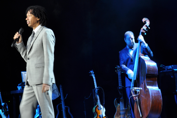 Imagem do cantor Djavan cantando durante show