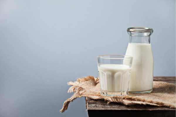 Jarra de vidro cheio de leite e um copo de leite em cima de uma messa