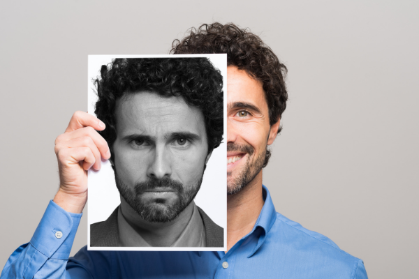 Homem sorrindo e segurando uma foto dele sério