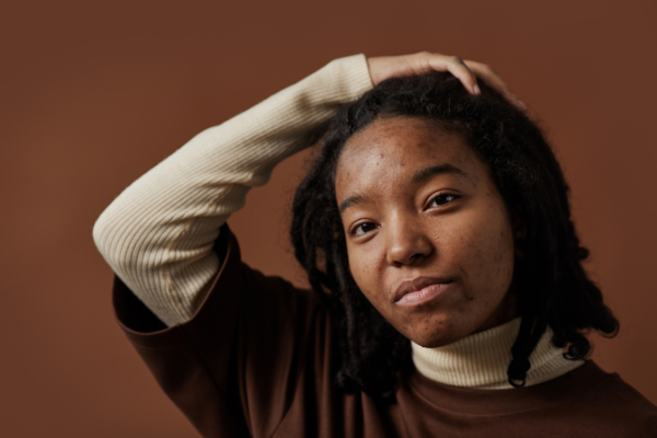 Mulher olhando para a câmera, com a mão na cabeça e semblante sério