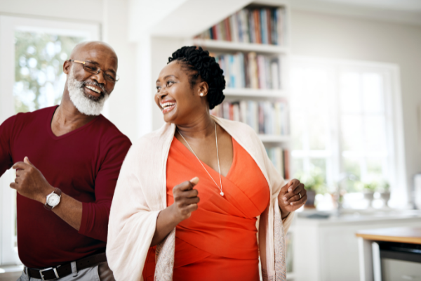 Imagem de um homem e uma mulher sorrindo e se divertindo em uma casa