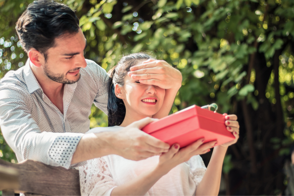 Homem surpreendendo mulher com um presente