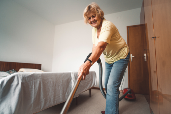 Mulher mais velha passando aspirador de pó em um carpete