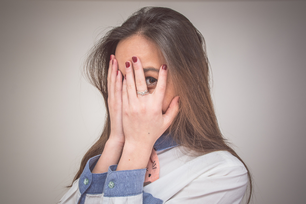 Menina escondendo o rosto com as mãos