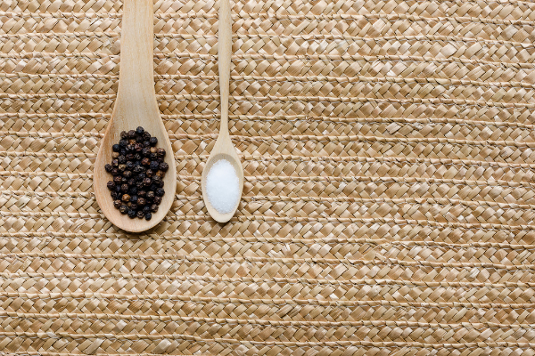 Pimenta-do-reino preta e sal em colheres de madeira
