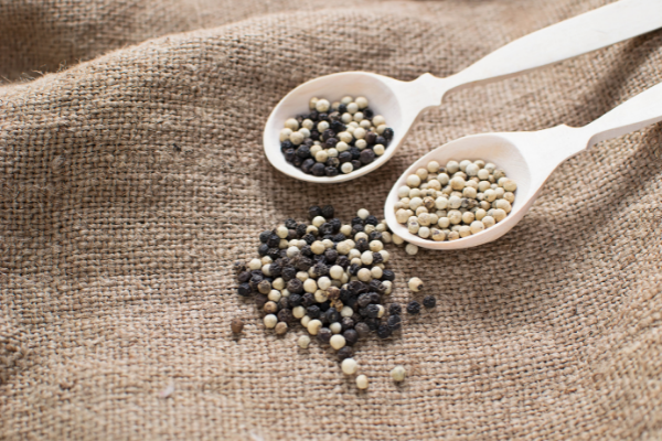 Pimenta-do-reino preta e branca dentro de colheres brancas