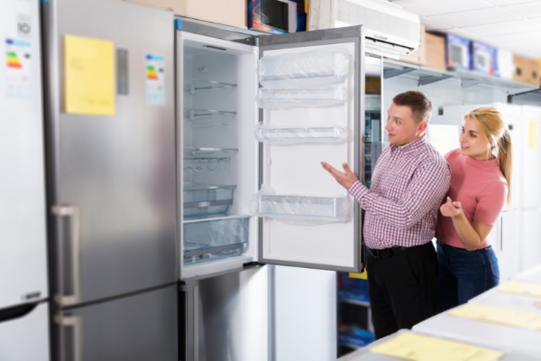 Casal abrindo uma geladeira nova na loja