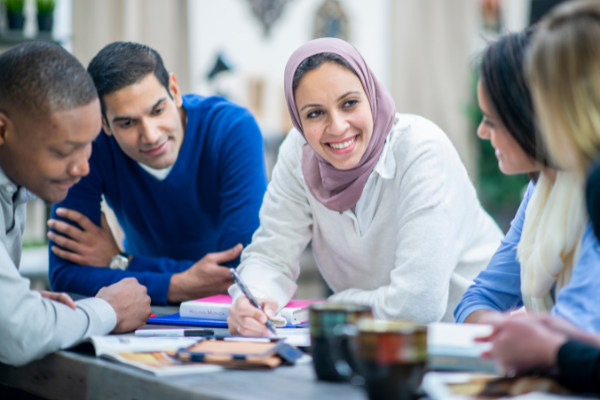 Pessoas sentadas em uma mesa com livros conversando