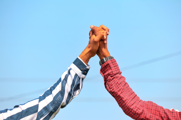Duas pessoas com as mãos juntas para cima