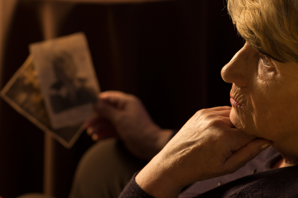 Imagem de uma senhora sentada segurando algumas fotos 