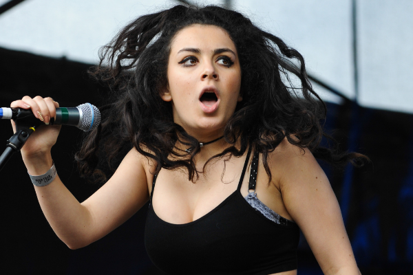 Imagem da cantora Charli XCX cantando durante um show