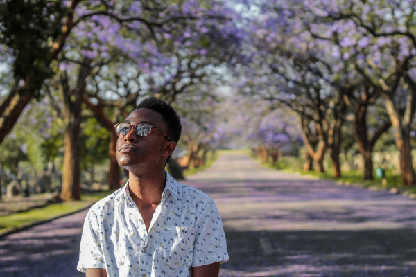 Homem de óculos andando em um parque e olhando para cima
