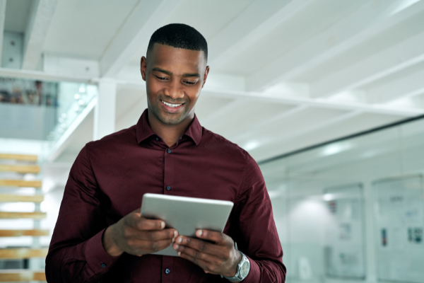 Homem sorrindo olhando para um tablet