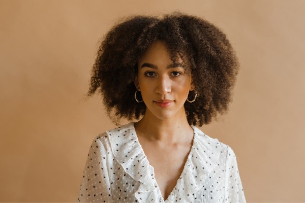 Mulher levemente maquiada olhando sério para a câmera