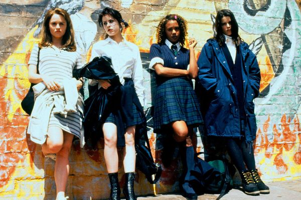 Quatro personagens do filme apoiadas sob um muro