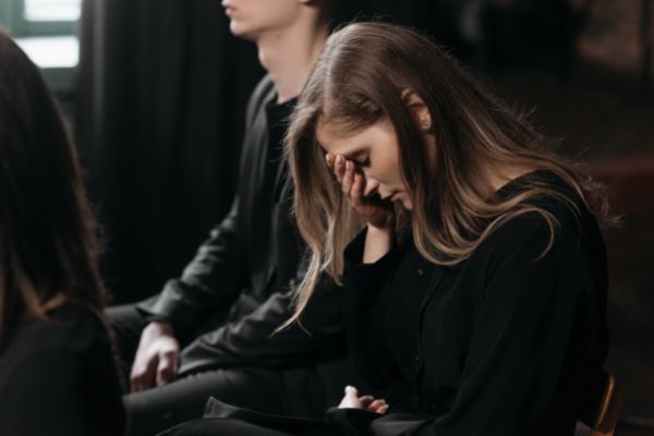 Mulher com a cabeça abaixada em um velório