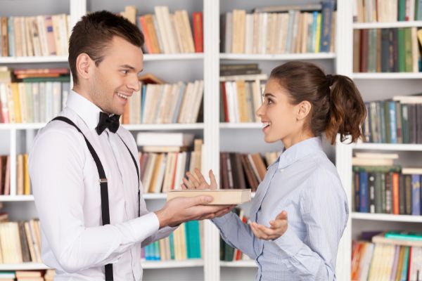 Homem entregando um livro para uma mulher