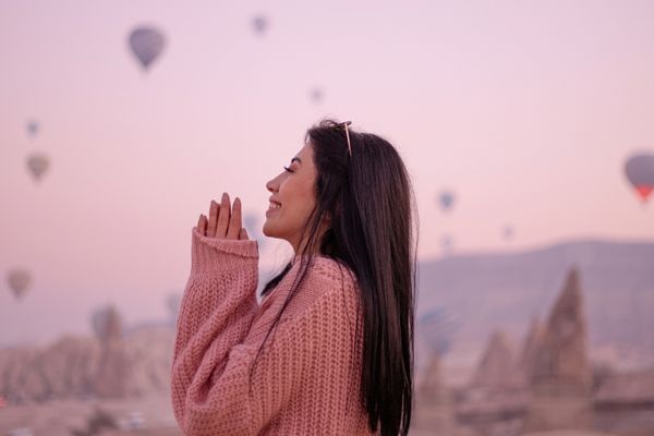 Mulher sorrindo. Ao fundo, é possível ver balões no céu