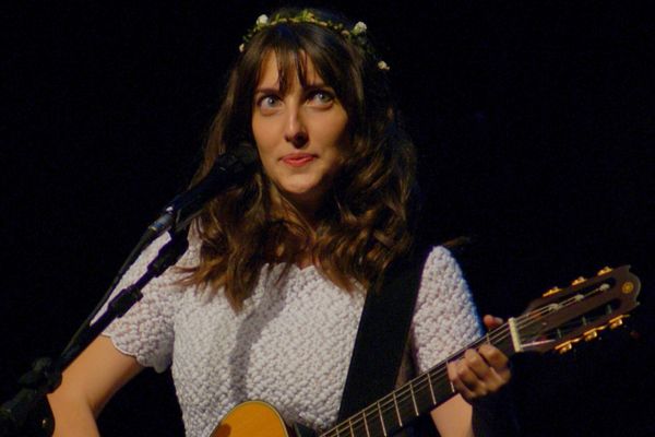 Clarice Falcão tocando violão e cantando em um show
