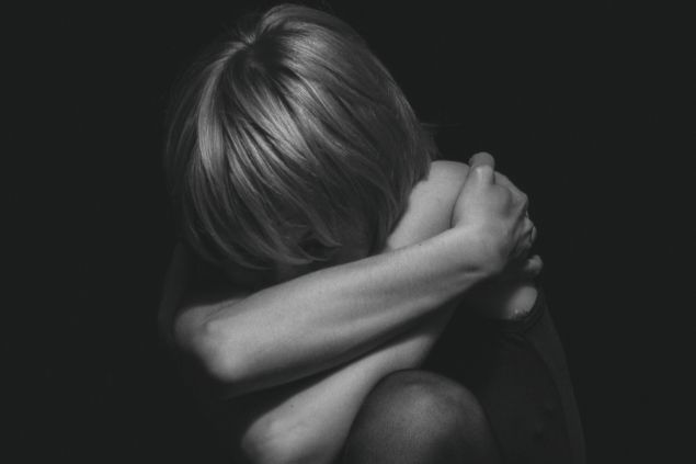 Imagem em preto e branco de uma pessoa cabisbaixo e acuada 