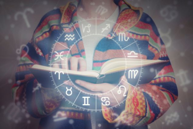 Imagem de uma pessoa segurando um livro e a sua frente o zodíaco com os signos