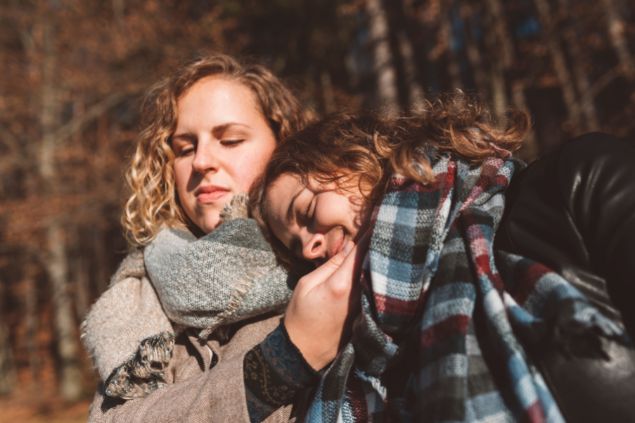Imagem de duas amigas uma com a cabeça recostada no ombro da outra