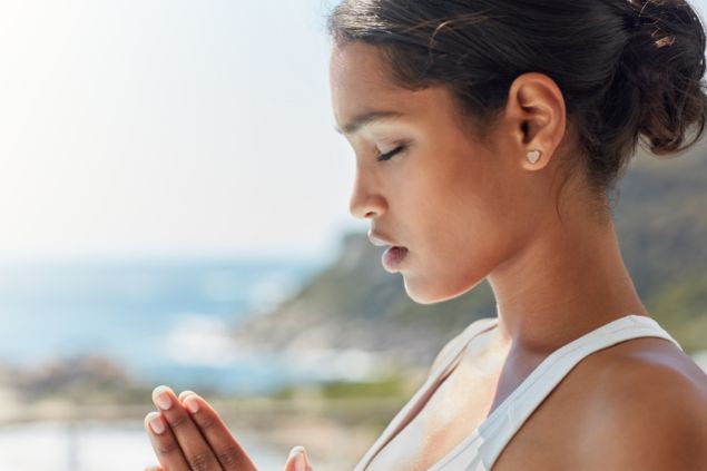 Imagem de uma mulher que parece estar fazendo oração com as mãos juntas e olhos fechados